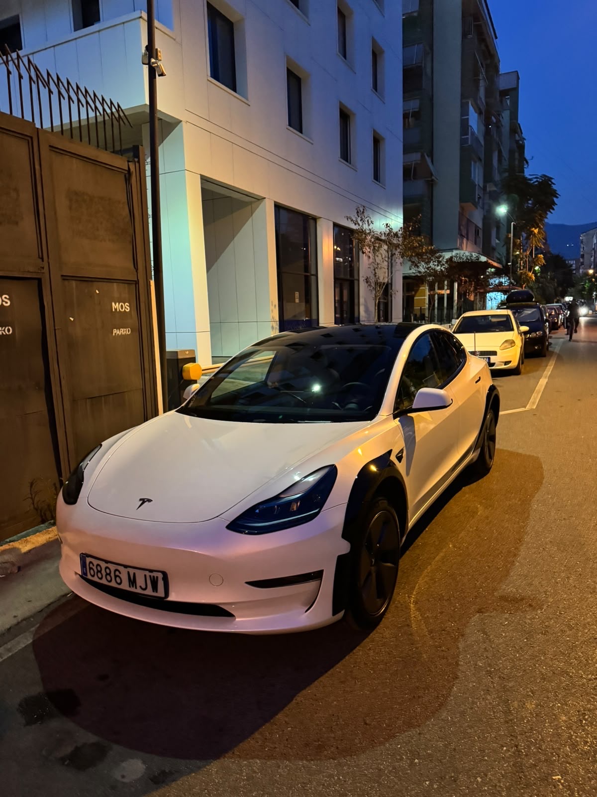 White Tesla Model 3 parked on a European city street at night